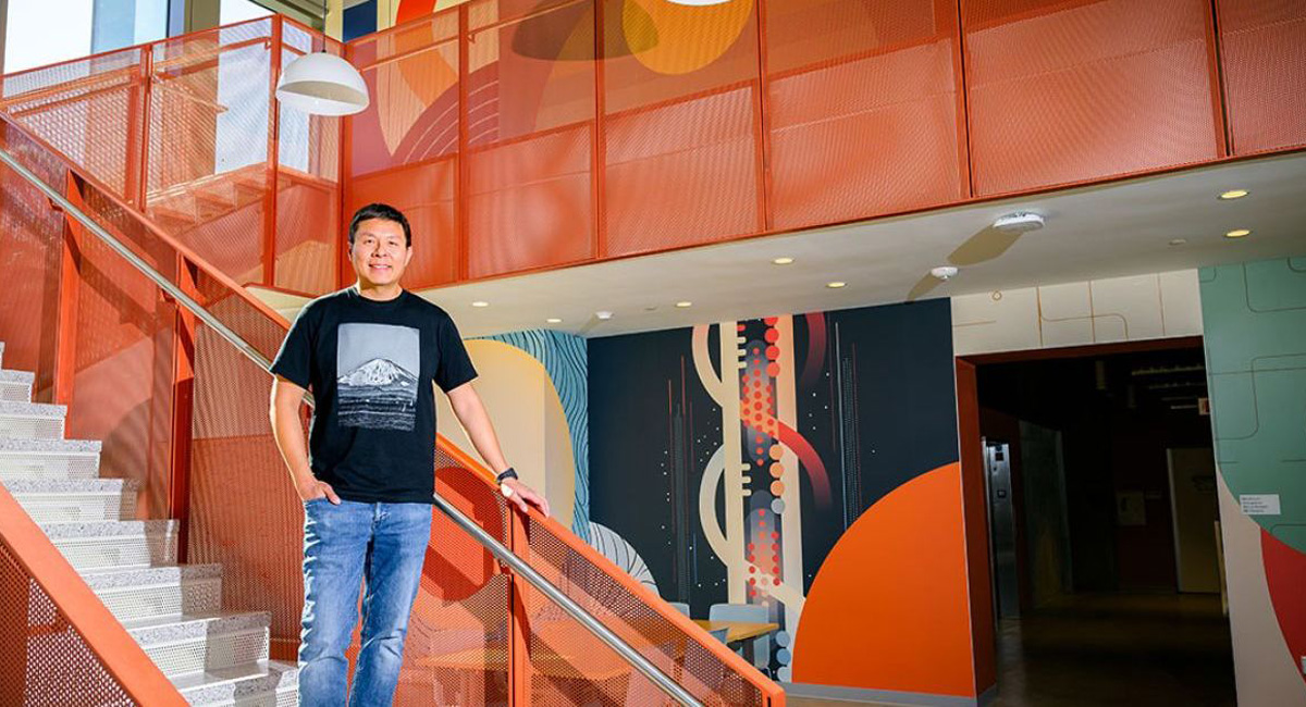 Brian Choi standing on stairs next to mural